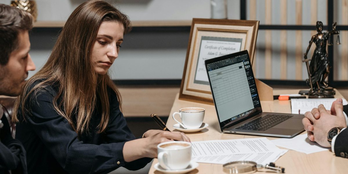 Two individuals, possibly tenants and an agent, engaged in a focused discussion over documents at a table, representing the negotiation phase of renting.