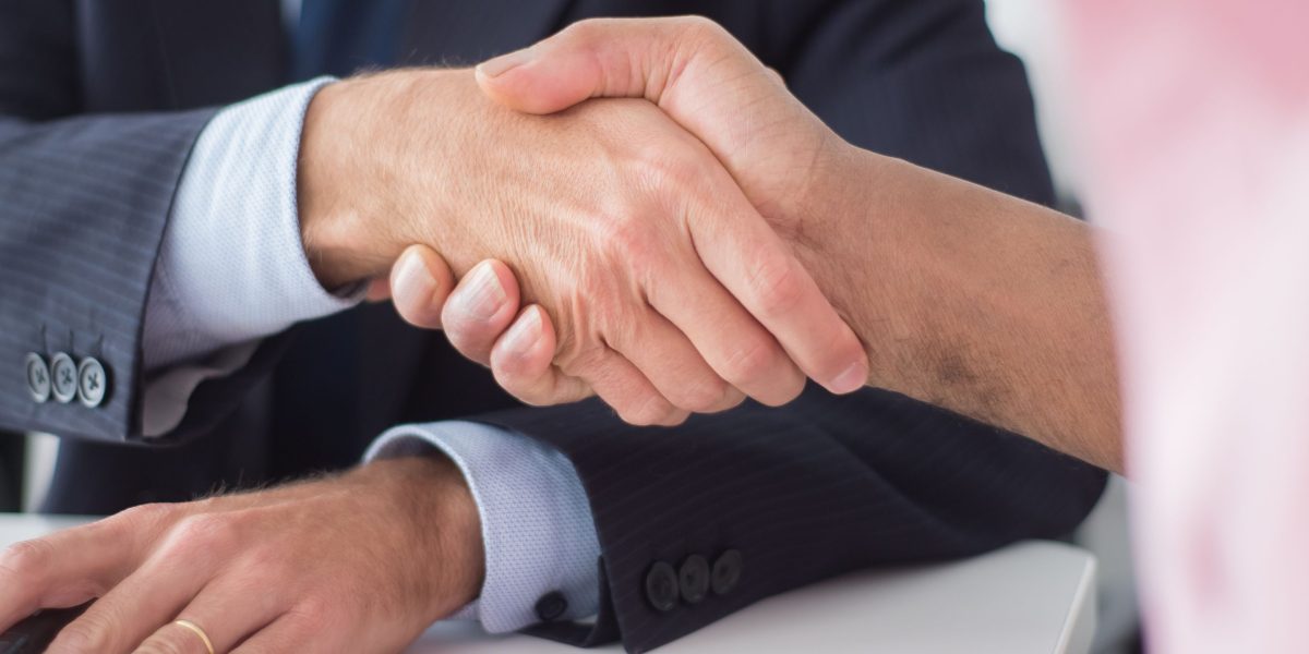 Two professionals shaking hands after a successful meeting, symbolizing a trusting partnership with a real estate agent.